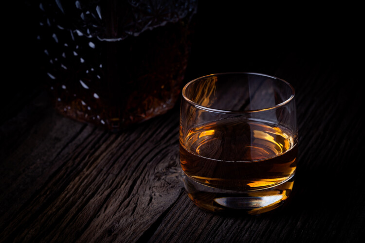 Fotografia reklamowa 13 Pomysłowe zdjęcie szklanki z whisky w ciemnej stylizacji na drewnianym stole